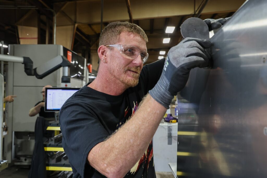 Fabricator handling a sheet metal part on the shop floor