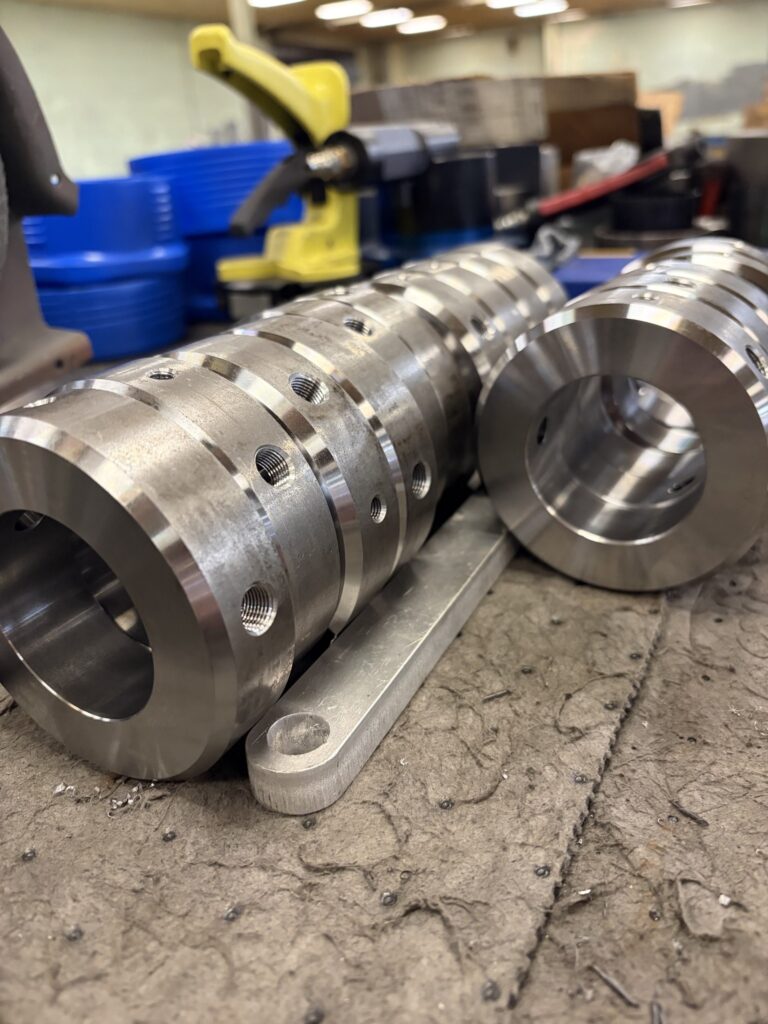 CNC-machined steel rings with drilled and tapped holes lined up on a shop bench