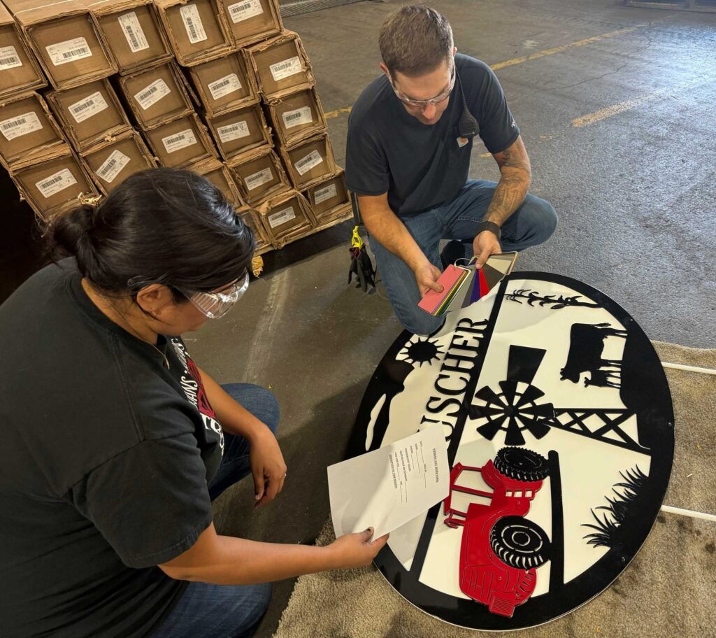 Red Oak team members checking a cut steel sign against its drawing