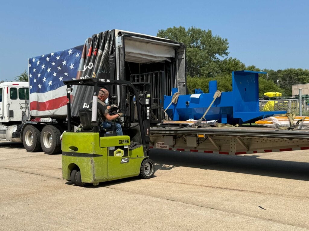 Forklift loading a fabricated assembly onto a flatbed trailer