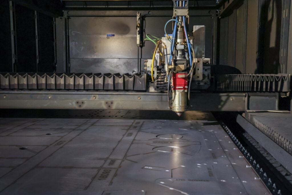 Laser cutting head over a steel plate on the cutting bed