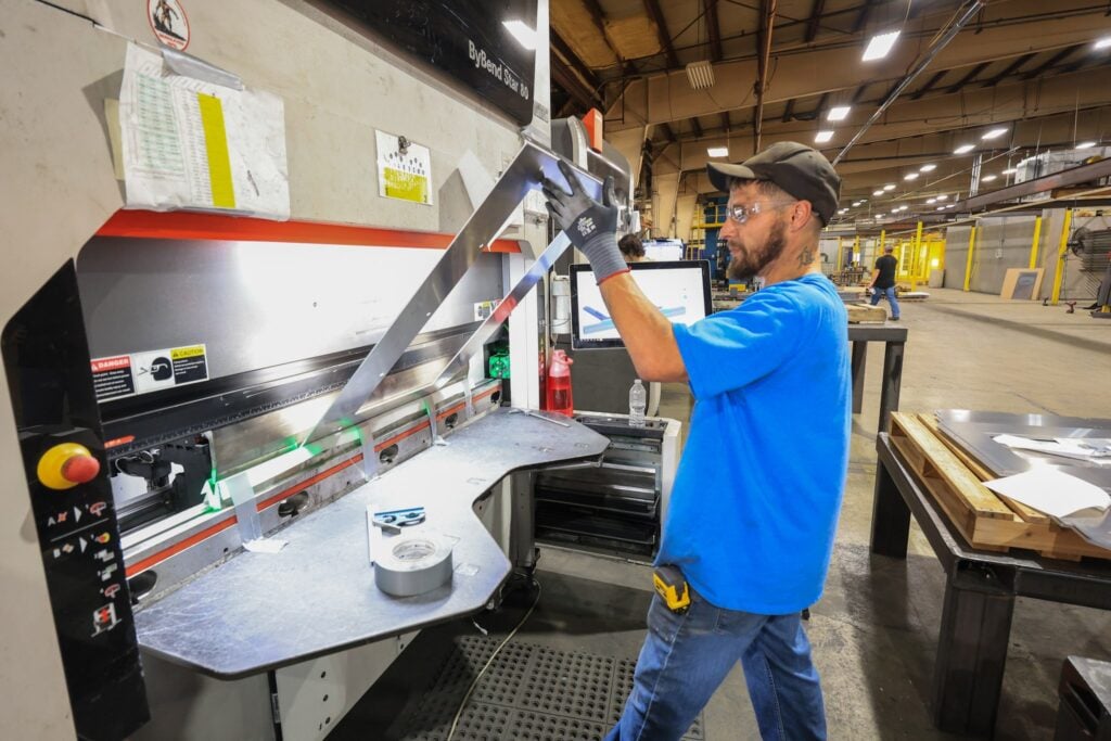 Operator bending a steel part on a press brake
