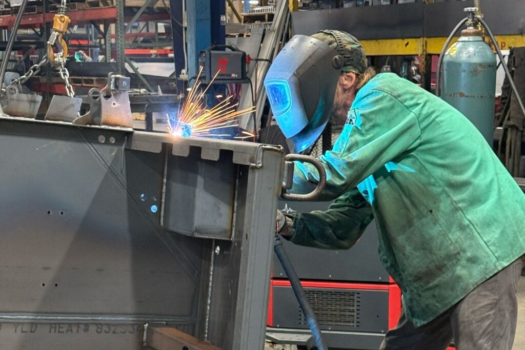 Welder in a protective jacket welding a steel assembly