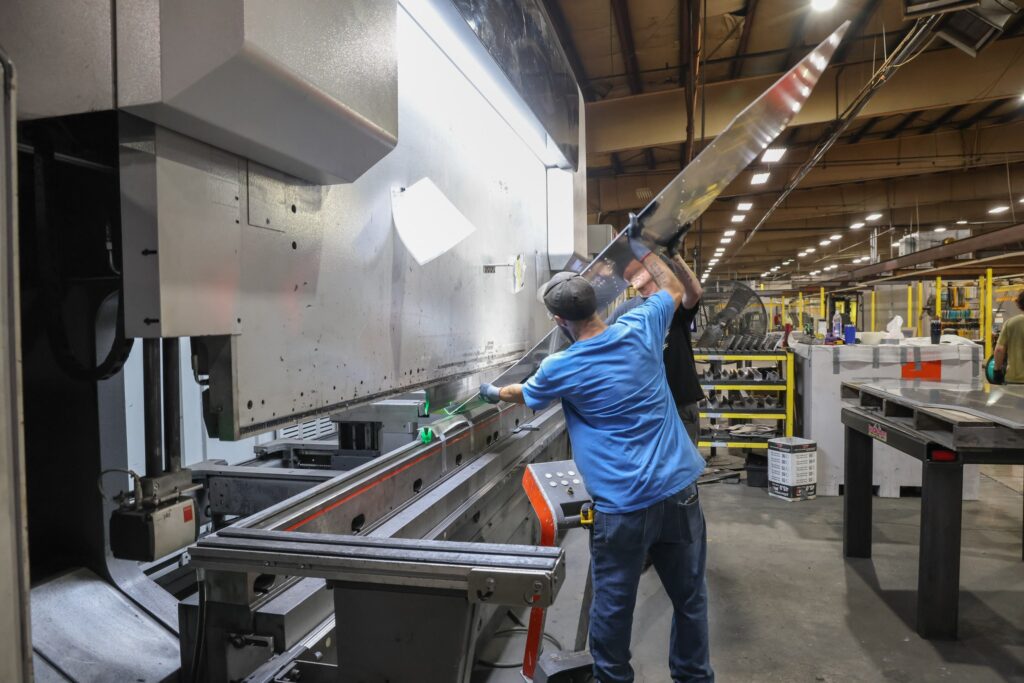 Operator forming a long steel part on a CNC press brake