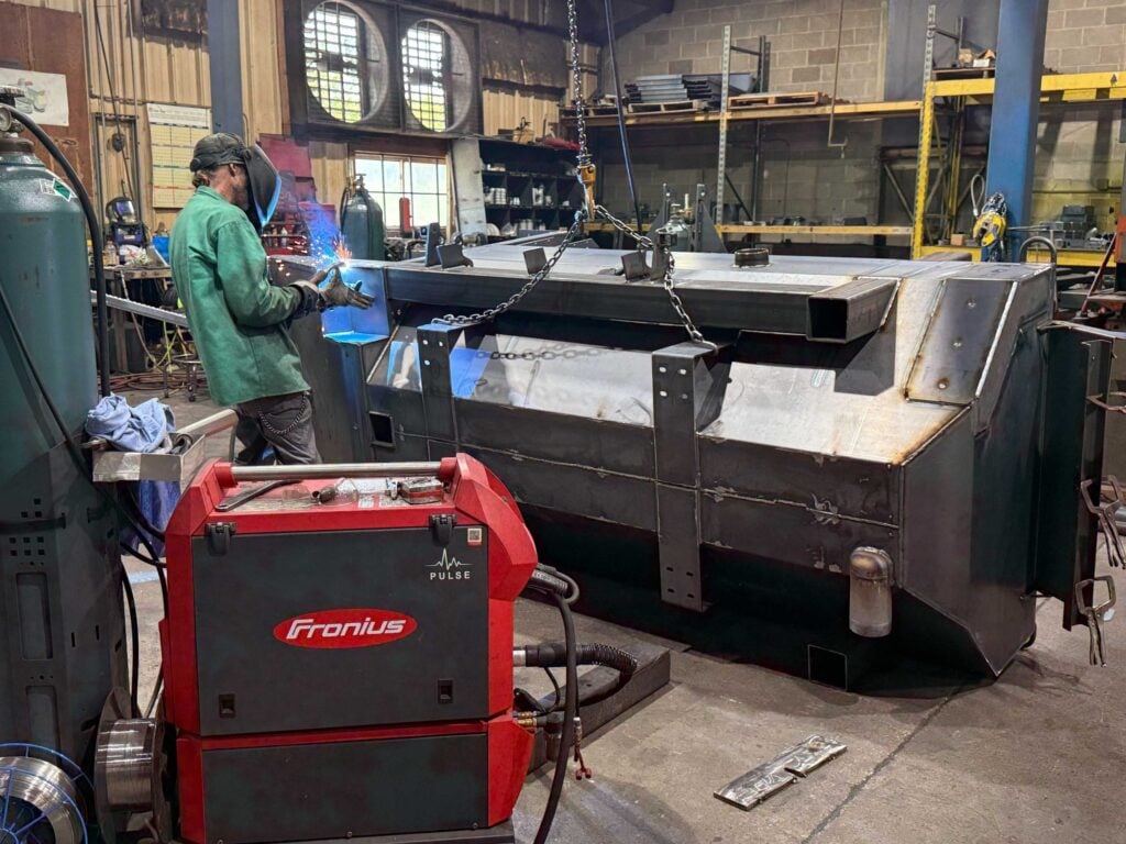 Welder working on a large steel assembly in the welding bay